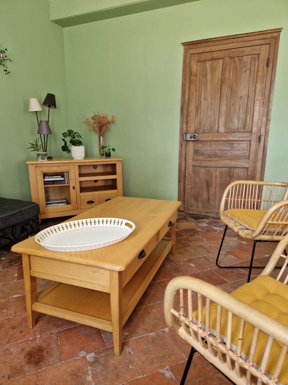 Le salon : table basse, fauteuils de rotin, vieille porte de bois