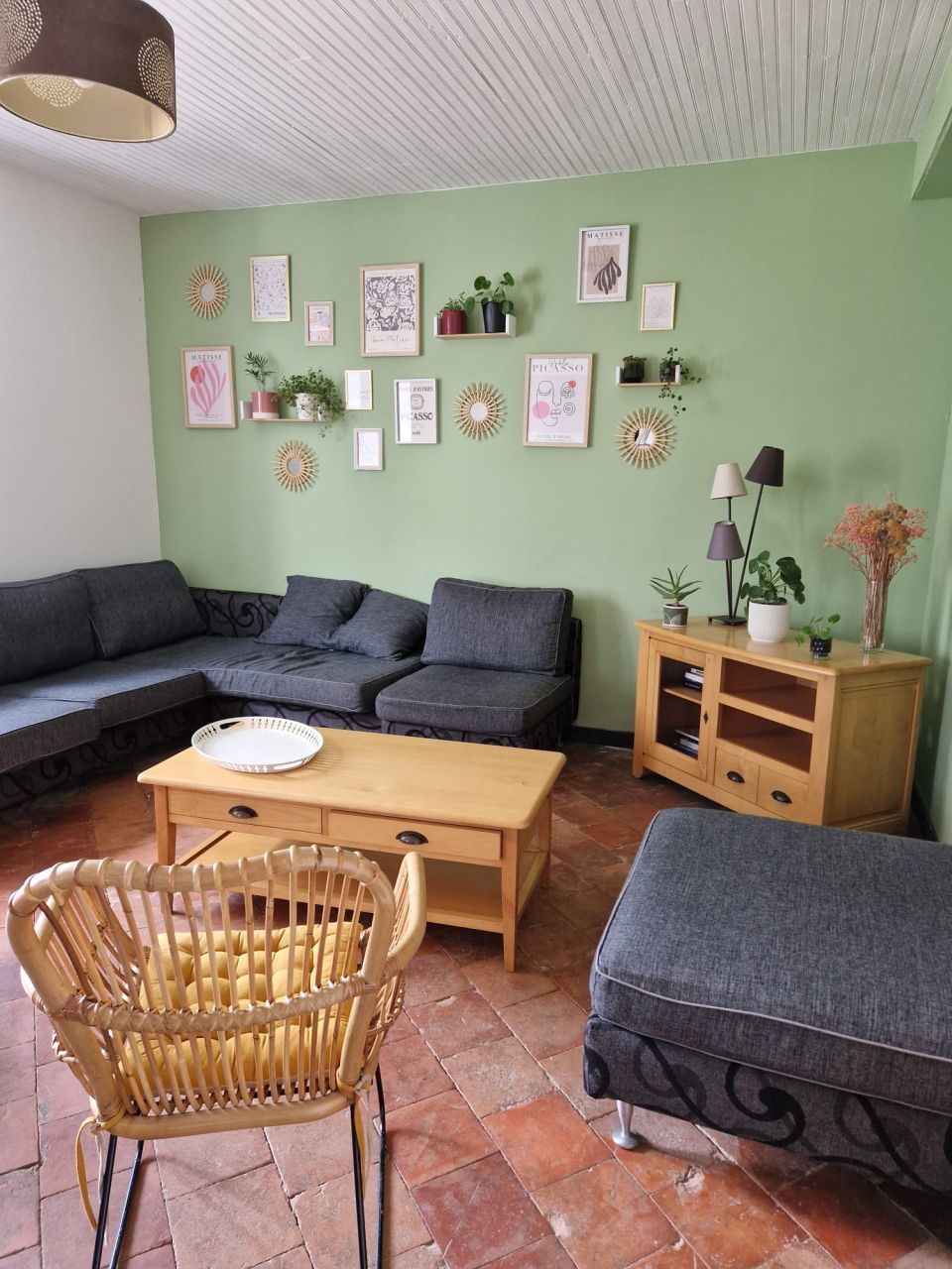 Le grand salon, murs vert d’eau, canapés gris et sol de tomettes